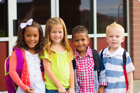 diverse group of young children outside a school